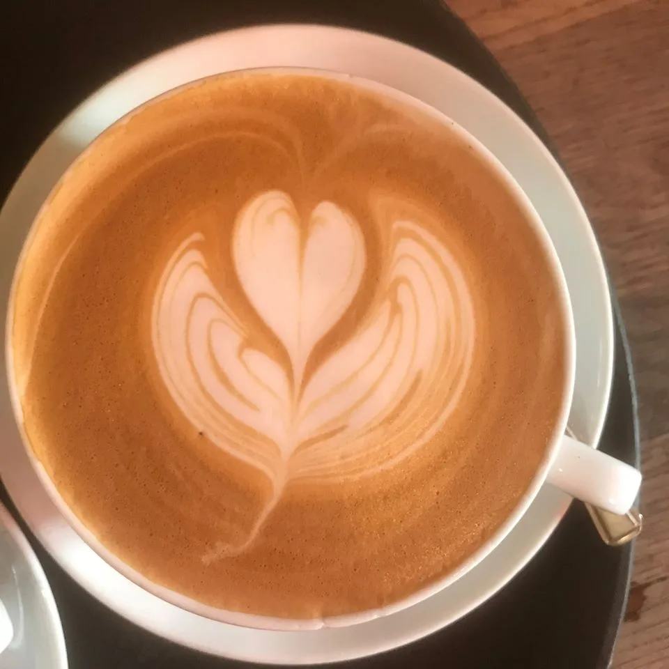 A flat white with heart-shaped latte art in a white cup