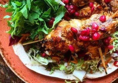 A plate of roasted chicken with a fresh salad and pomegranate seeds