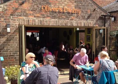Customers sitting at tables outside the open doors of the cafe on a sunny day